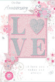 This anniversary card appears like a gentle celebration of lasting romance, echoing the soft, pastel hues of a spring morning along Bankside. It blends delicate pinks and silvery greys into a serene composition that radiates intimacy. At its centre, the word LOVE is formed in raised, softly glittering letters, each one subtly textured as if dusted with fine sugar. The O is replaced by a shimmering silver heart, thickly textured with glitter that catches the light like city lights reflecting on the Thames near Southwark Bridge. Around this heartfelt focal point, a constellation of delicate blooms opens in blush and mauve tones, their edges softly blurred as if painted in watercolour. Fine, flowing lines define each petal and stem, recalling the careful attention of a florist crafting an anniversary bouquet for a couple living near Borough High Street. Slender swirls, scattered petals, and almost hidden butterflies weave through the florals, adding a sense of motion and whimsy, like petals stirred by a gentle evening breeze from the river. The phrases On Our Anniversary and I love you today and always are rendered in a refined, flowing script, their curves echoing the lines of the vines and stems so that text and illustration feel seamlessly intertwined. The background remains a tender, muted pink, providing a calm canvas that allows the silver accents and soft florals to stand out. Overall, the card feels like a cherished memento of shared years and quiet promises, beautifully suited to accompany flowers delivered across Bankside, from Tate Modern to the hidden streets of London Bridge.